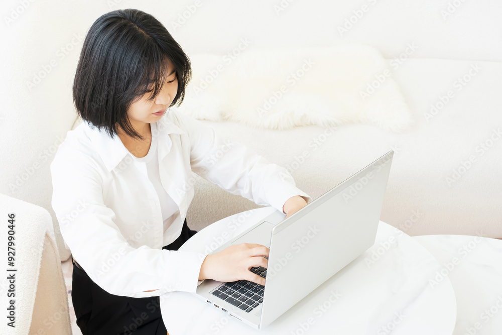 Young Asian woman typing on laptop in her apartment top view work from home concept. Young Asian woman typing on laptop in her apartment top view work from home concept.