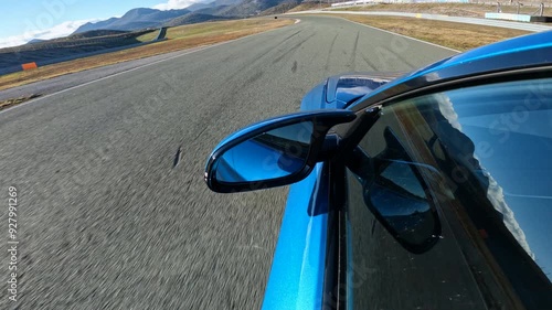 CLOSE UP, LENS FLARE: Sports car races along the scenic closed circuit on a perfect autumn day. Bright sunbeams shine on metallic blue sportscar driving along the winding high-speed asphalt racetrack. photo