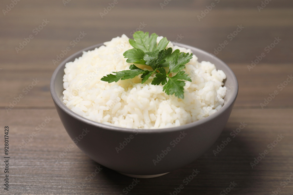 Bowl of delicious boiled rice with parsley on wooden table, closeup Bowl of delicious boiled rice with parsley on wooden table, closeup