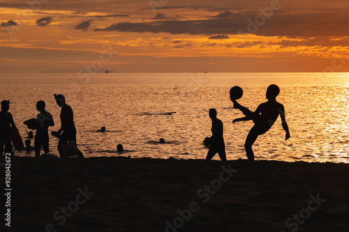 Silhouette of an Asian male player with a ball playing traditional sepak takraw football on the beach by the sea at sunrise photo