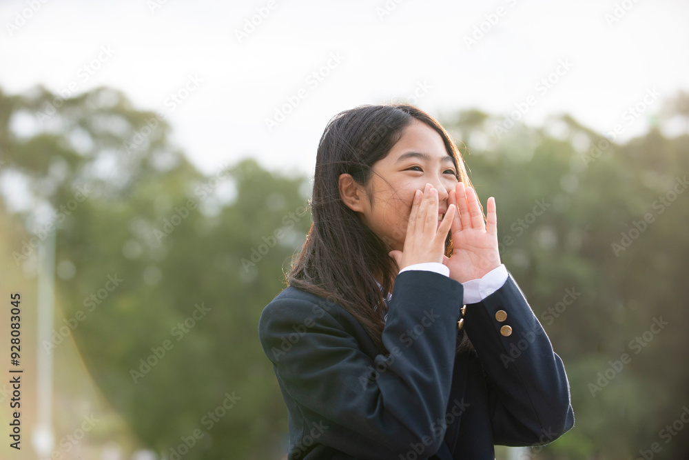 手を添えて声を出している制服姿の女子学生