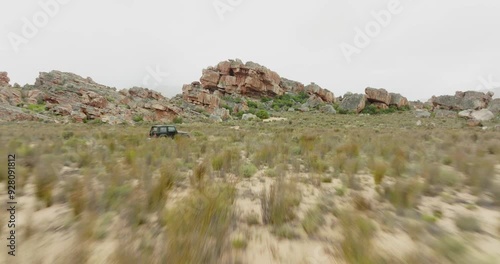 Drone flies fast over desert landscape in Cederberg Wilderness Area south africa and pursues a black off-road vehicle - scenic landscape photo