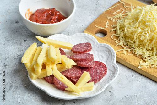 Ingredients for making pizza: grated cheese and sausage