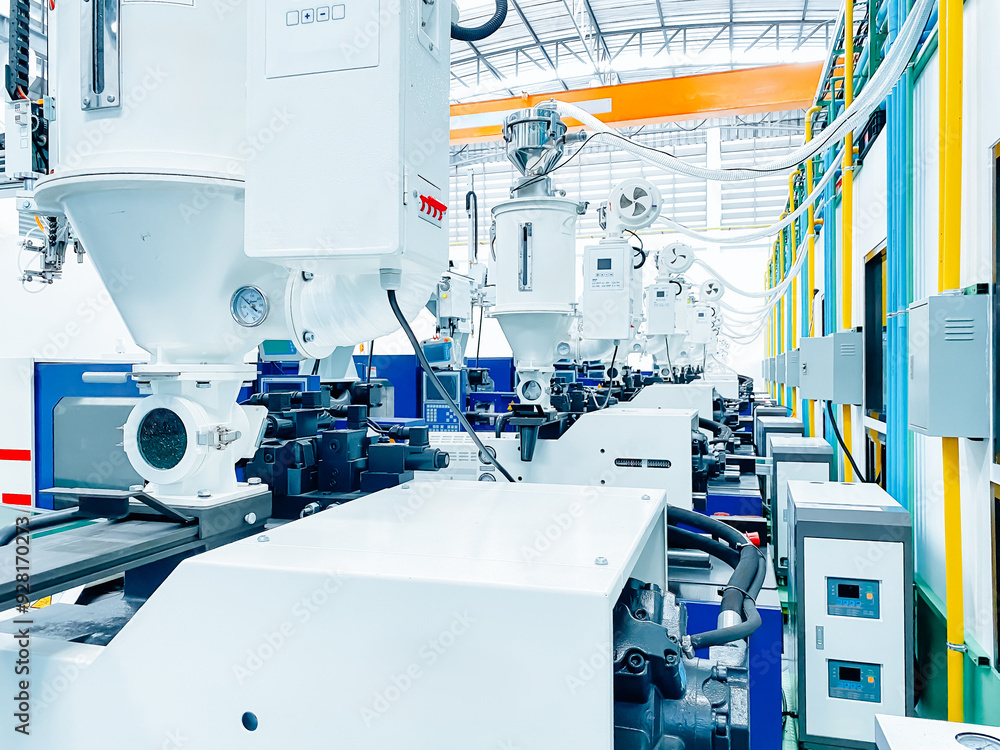 High-tech plastic injection molding machines lined up in a modern factory. High-tech plastic injection molding machines lined up in a modern factory.