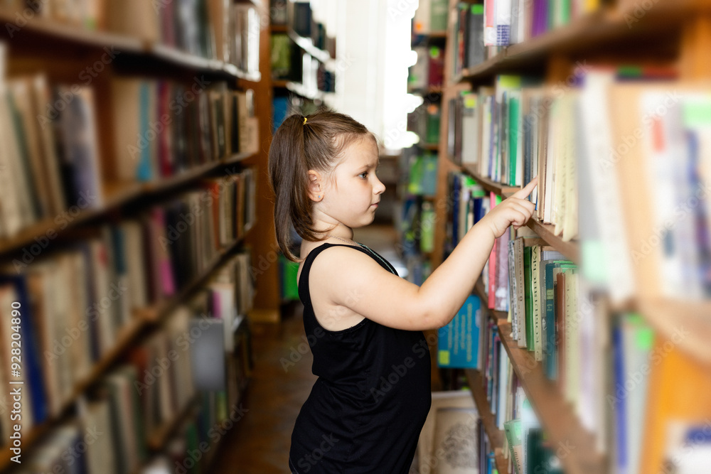 schoolgirl student in the library near the shelves with books. Education, science and learning concept. schoolgirl student in the library near the shelves with books. Education, science and learning concept.