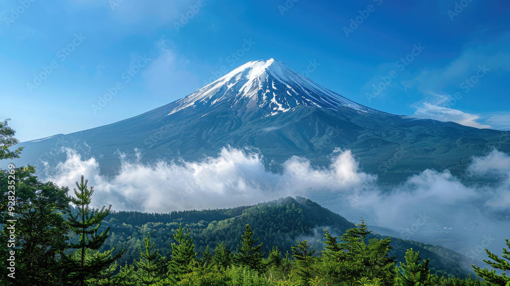 Mount Fuji in Japan wide landscape with blue sky, snow on the mountain top, green trees around the mountain, clouds and mist Mount Fuji in Japan wide landscape with blue sky, snow on the mountain top, green trees around the mountain, clouds and mist