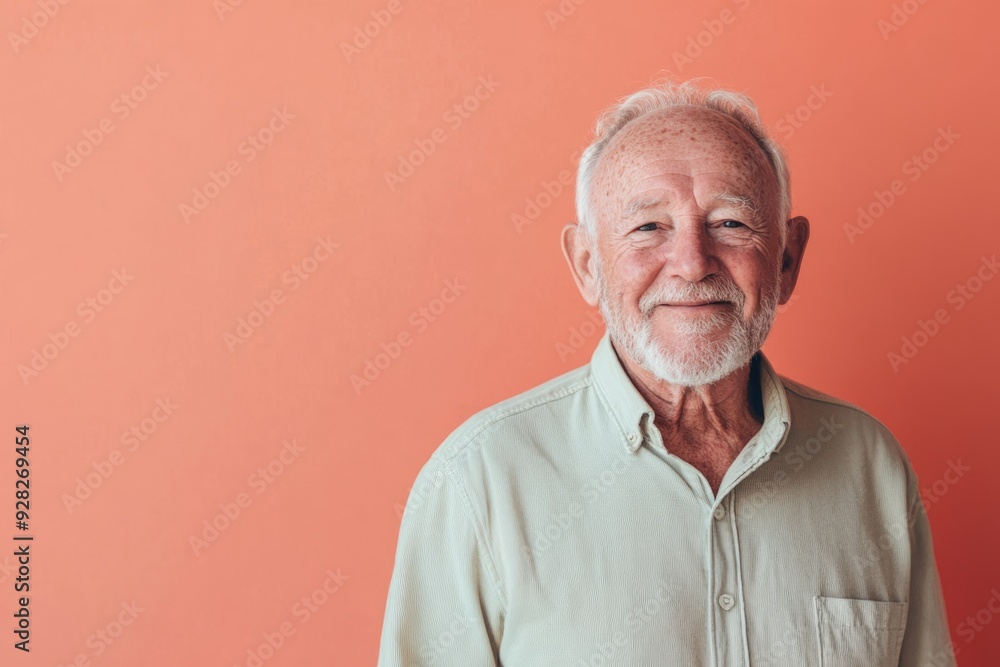 Elderly man, smiling warmly, standing against a solid light coral background with ample room for text Elderly man, smiling warmly, standing against a solid light coral background with ample room for text