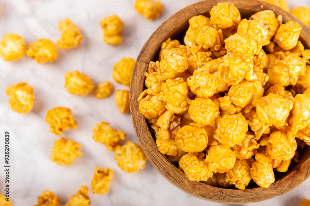 Sweet caramel popcorn in a bowl on a wooden background. Salted caramel popcorn. Caramel sauce. Close up. Topping. Place for text. Copy space Sweet caramel popcorn in a bowl on a wooden background. Salted caramel popcorn. Caramel sauce. Close up. Topping. Place for text. Copy space