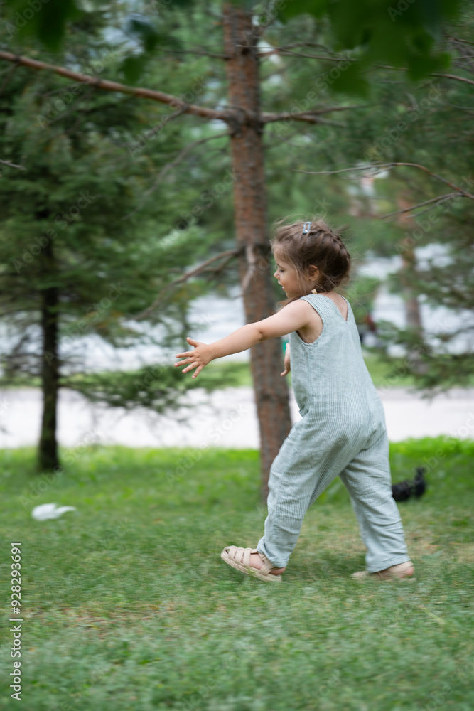A three-year-old girl runs after pigeons in the park. A three-year-old girl runs after pigeons in the park.