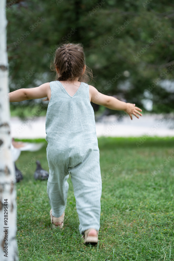 A three-year-old girl runs after pigeons in the park. A three-year-old girl runs after pigeons in the park.