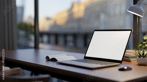 A laptop computer mockup on a wooden desk by the window in a room, illuminated by a table lamp.