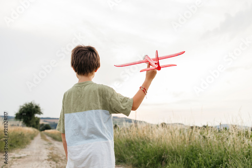 Boy playing with red airplane on field photo