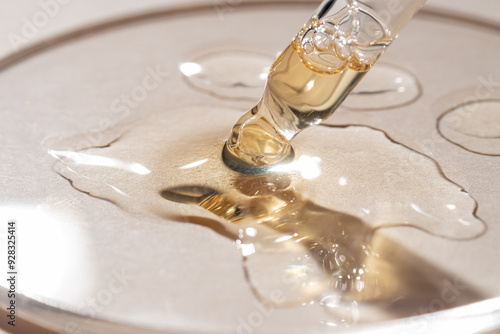 Bottle pipette dropper close up and Liquid yellow-orange retinol or vitamin c gel or serum on a beige background photo