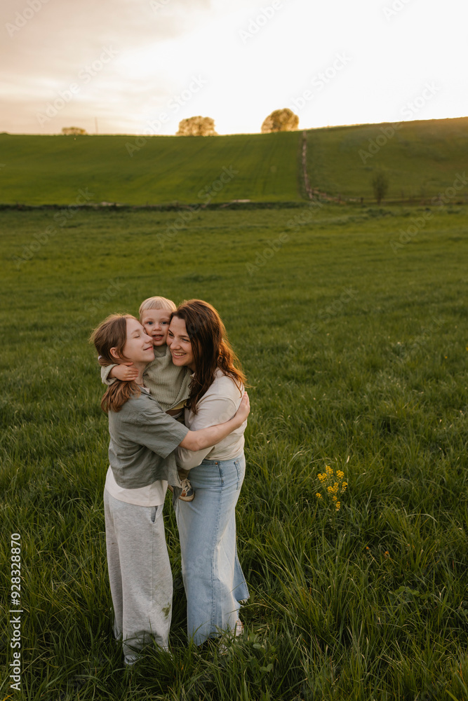Mother and daughter embracing baby at meadow Mother and daughter embracing baby at meadow