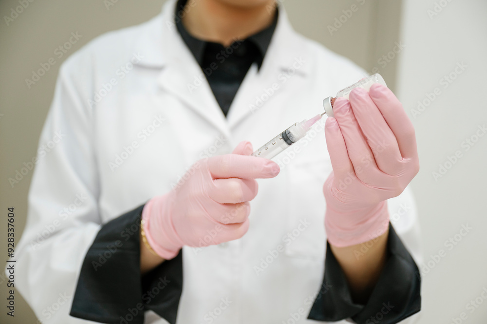 Aesthetician wearing glove and filling syringe through vial at clinic Aesthetician wearing glove and filling syringe through vial at clinic