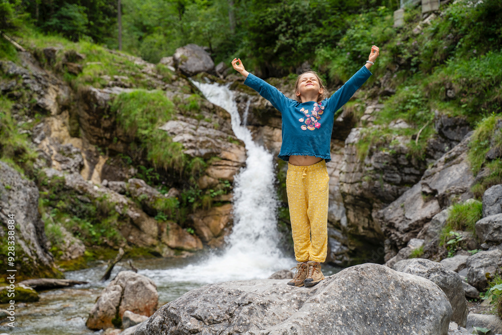 Carefree girl standing on rocks near flowing stream in forest Carefree girl standing on rocks near flowing stream in forest