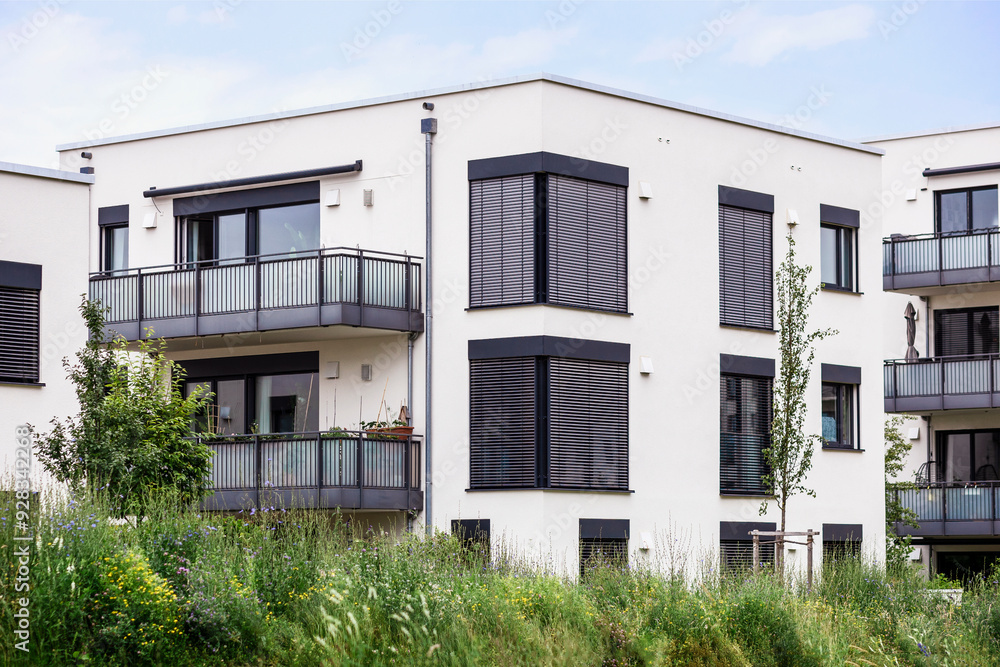 Residential Building. Modern Low rise Apartment Building. White Facade of Modern Apartments Block with Window Blinds, Modern Balcony and Green Landscaping. Residential Building. Modern Low rise Apartment Building. White Facade of Modern Apartments Block with Window Blinds, Modern Balcony and Green Landscaping.