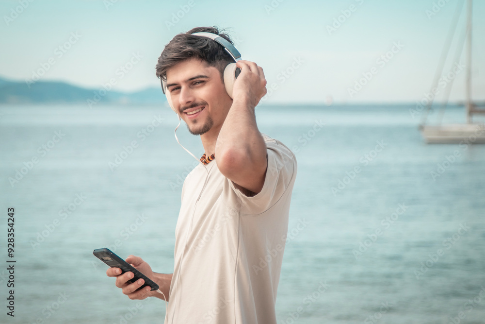 young man on beach with back turned wearing headphones... young man on beach with back turned wearing headphones...