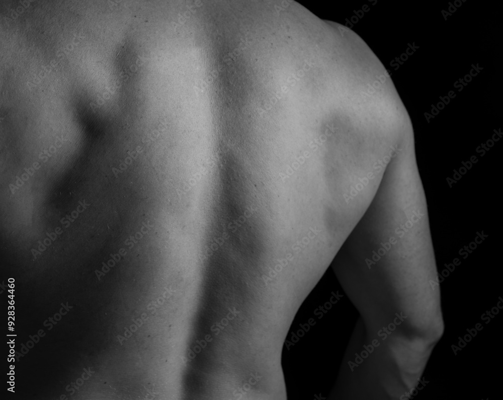Strong muscular man holding his hands behind his head. Perfect shoulders and back muscles. Dramatic light