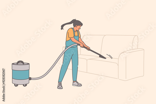 Woman maid uses vacuum cleaner to clean sofa from dust and disinfect upholstered furniture