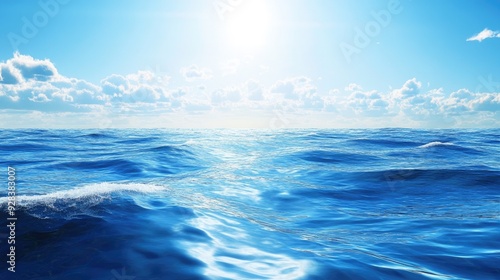 A blue sea with gentle waves and a clear, sunny sky reflecting on the water.