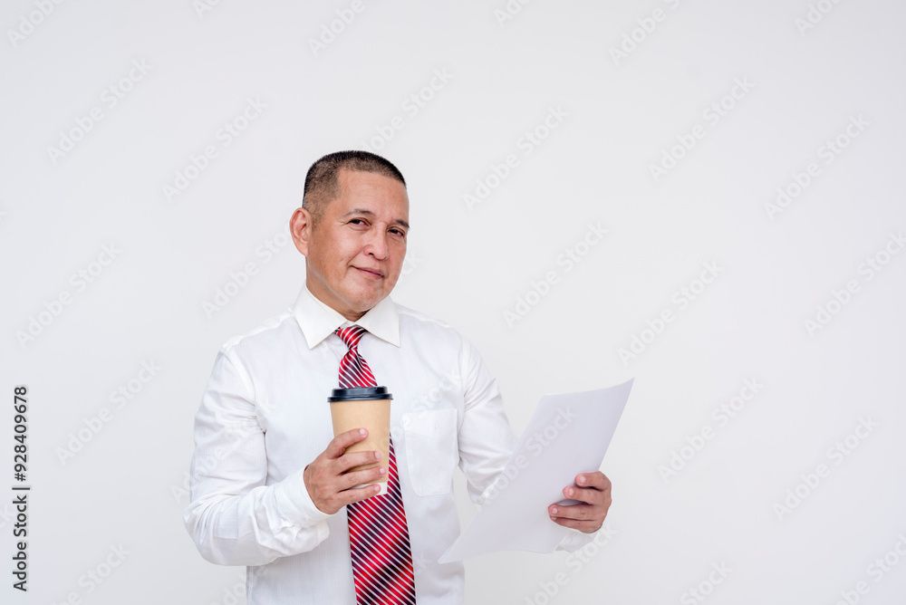 A middle aged asian manager looking at camera while reading a report or paper document while holding a cup of coffee. Isolated on a white background. A middle aged asian manager looking at camera while reading a report or paper document while holding a cup of coffee. Isolated on a white background.
