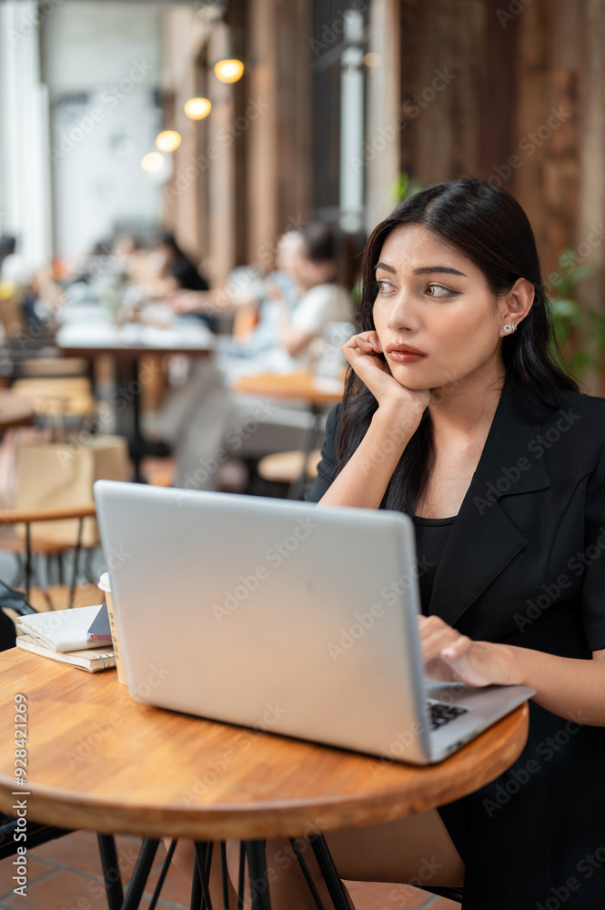 A thoughtful Asian businesswoman is concerned about her job while working remotely from a cafe. A thoughtful Asian businesswoman is concerned about her job while working remotely from a cafe.