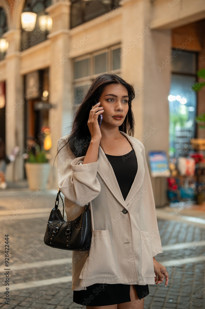 Gorgeous Asian businesswoman is talking on the phone while hurrying through the city, going to work. Gorgeous Asian businesswoman is talking on the phone while hurrying through the city, going to work.
