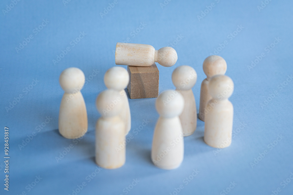 People figurines or toy blocks with one lying down on podium. Failure or dead leadership concept. People figurines or toy blocks with one lying down on podium. Failure or dead leadership concept.