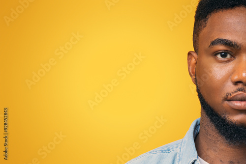 Half face portrait of confident african american man with beard on yellow studio background, free space