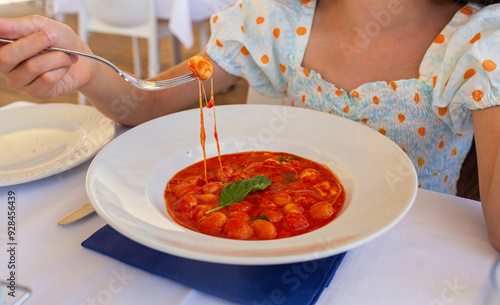 Girl eating famouse potato Gnocchi alla Sorrentina in the south italian restaurant. Is a dish from Campania, Italy, prepared with potato dumplings with tomato sauce, mozzarella and basil leaves. photo