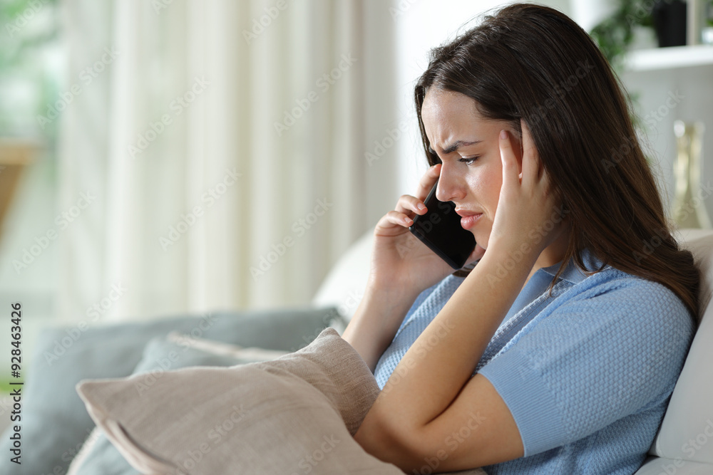 Worried woman attending phone call at home Worried woman attending phone call at home