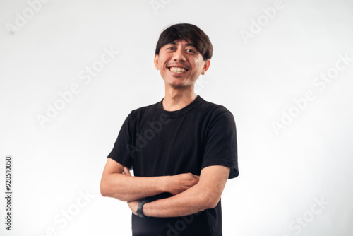 A smiling Asian man in a black t-shirt stands confidently with arms crossed against a plain white background, ideal for professional headshots, personal branding, or business profile content