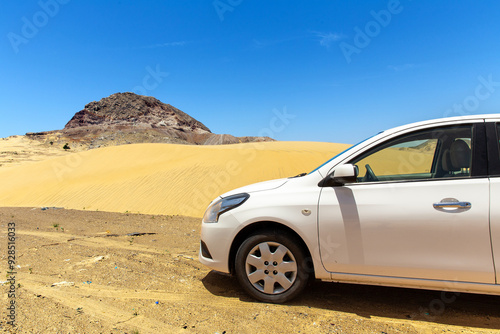 White passenger car against the background of sand dune in the desert on a hot sunny day. Sultanate of Oman