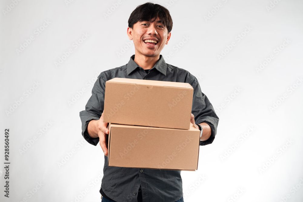 Asian man in a dark gray shirt holding out a plain cardboard box with both hands, standing against a white background. The box is central to the image, suggesting delivery, packaging, or a gift. Asian man in a dark gray shirt holding out a plain cardboard box with both hands, standing against a white background. The box is central to the image, suggesting delivery, packaging, or a gift.