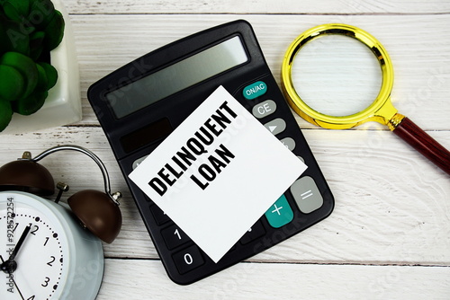 Photos Delinquent Loan text message with calculate, alarm clock and magnifying glass on