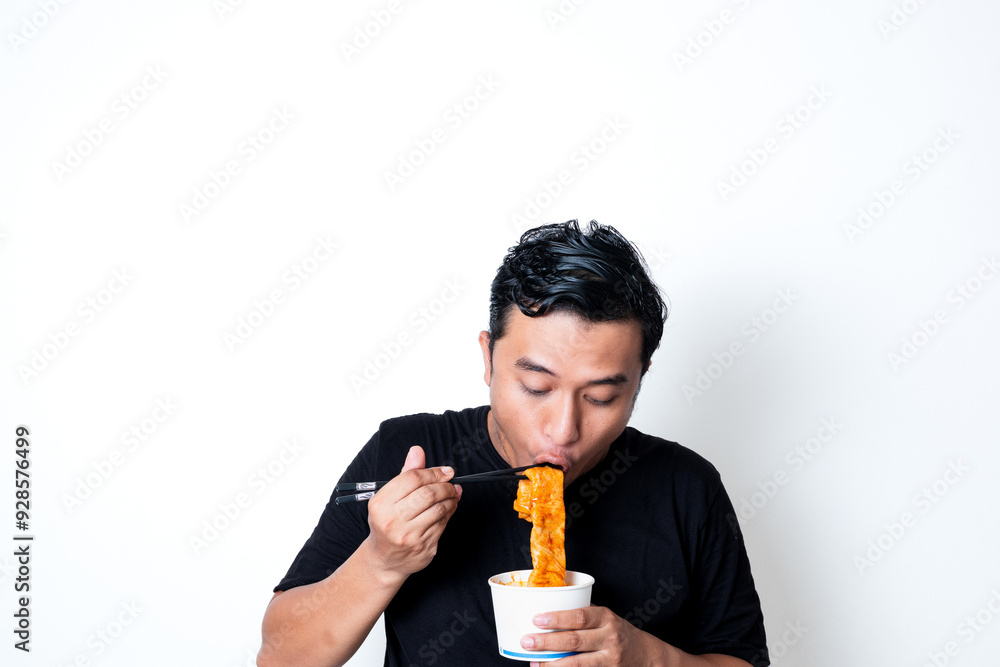 Asian adult man wearing a black t-shirt posing eating Korean specialty food odeng isolated white background
