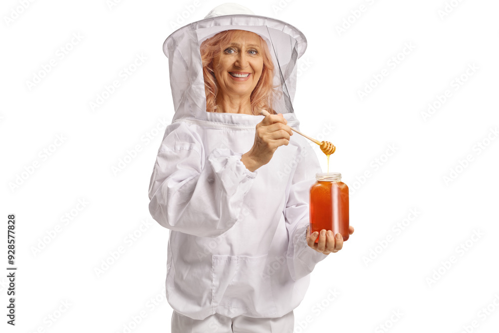Bee keeper in a uniform trying honey from a jar of honey and smiling Bee keeper in a uniform trying honey from a jar of honey and smiling