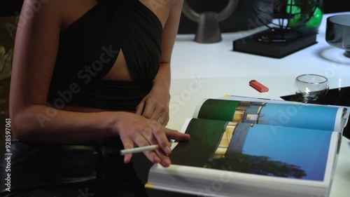 Young beautiful female fashion model smoke the cigarette. pretty woman wears elegant black clothes and reads the book