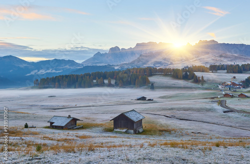 Aerial autumn sunrise scenery with yellow larches and small alpine building and Odle - Geisler mountain group on background. Alpe di Siusi, Dolomite Alps, Italy. photo