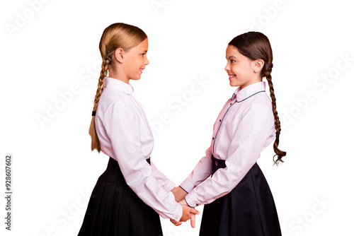 Profile side view of two person nice attractive charming cute lovely winsome adorable cheerful cheery friendly pre-teen girls holding hands isolated over bright vivid shine orange background photo