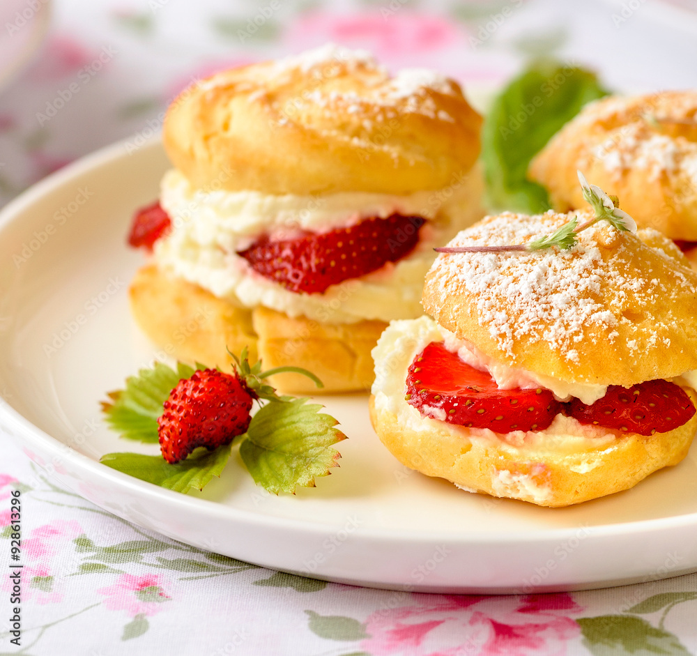 Cream puffs cakes or profiterole filled with whipped cream and served with strawberries and tea on the table
Cream puffs cakes or profiterole filled with whipped cream and served with strawberries and tea on the table