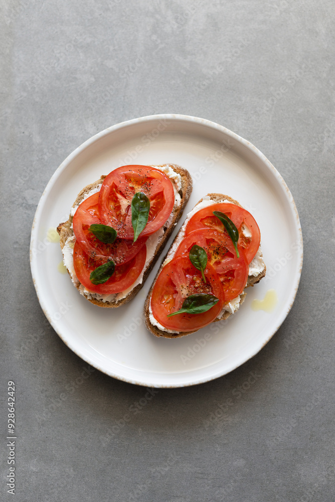 Breakfast toasts with cream cheese, fresh tomato, olive oil and baby spinach on a white plate. Healthy tasty food concept, top view Breakfast toasts with cream cheese, fresh tomato, olive oil and baby spinach on a white plate. Healthy tasty food concept, top view