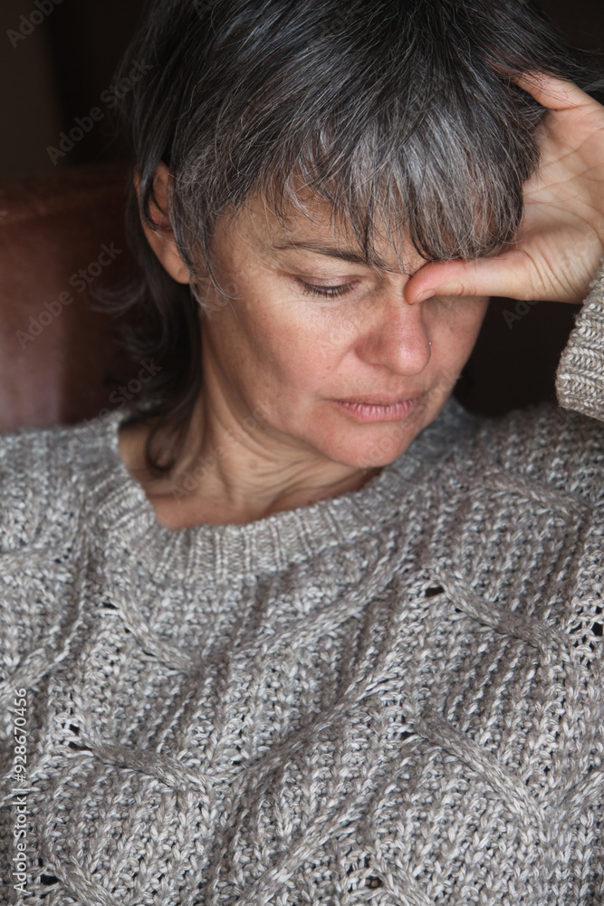 close up portrait of depressed middle-aged woman with grey hair sitting on a couch thinking close up portrait of depressed middle-aged woman with grey hair sitting on a couch thinking