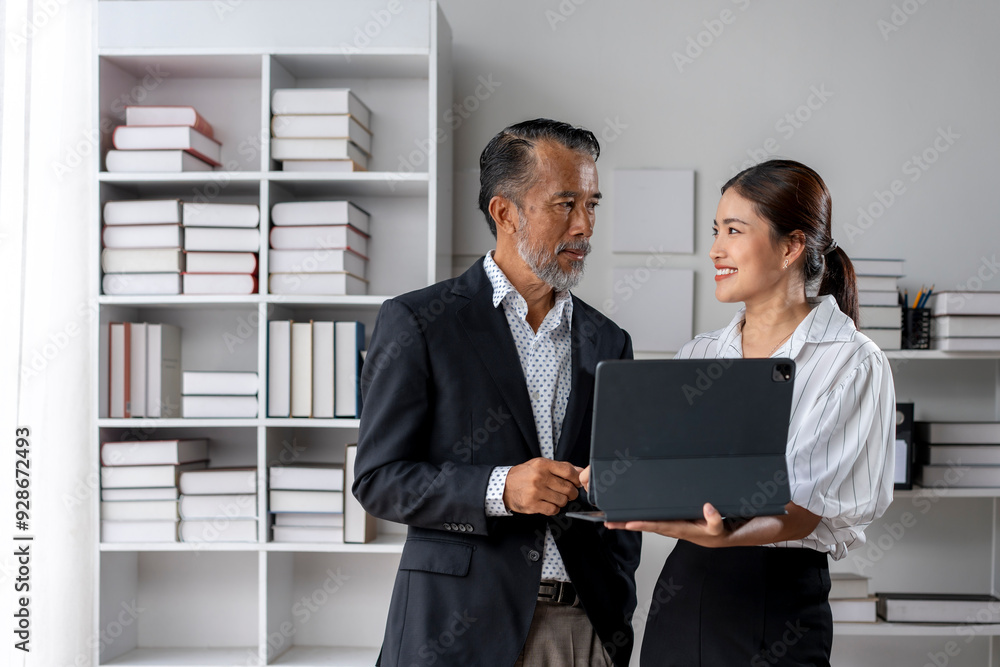 Two people in a business setting, one holding a laptop Two people in a business setting, one holding a laptop