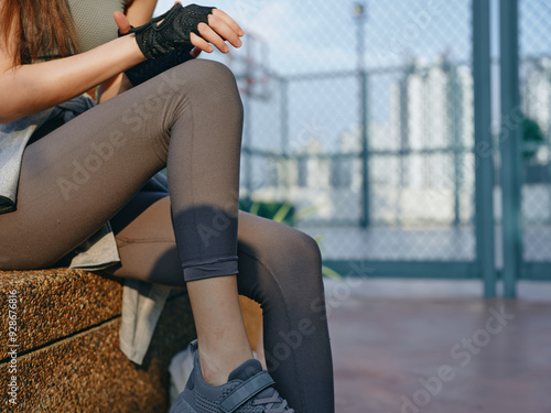 Woman resting after workout in sport outfit near urban gym photo