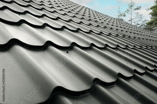 Close-up house roof with steel roofing sheet. Gray modular tile effect roof panel. Traditional metal shingle tiles. Profiled metallic corrugated pantile as clay or concrete slate. Building's covering photo