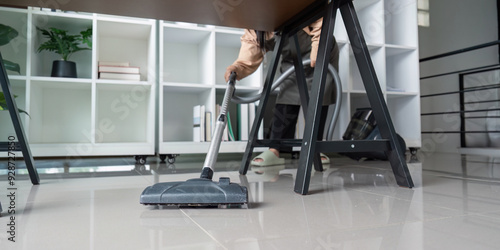 Maid Skillfully Vacuuming Under Desk in Modern Office Environment photo