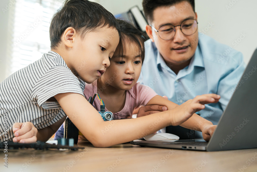 A boy and girl are learning to build robot toys with their dad in the living room. Robot model, learning, future, AI technology A boy and girl are learning to build robot toys with their dad in the living room. Robot model, learning, future, AI technology