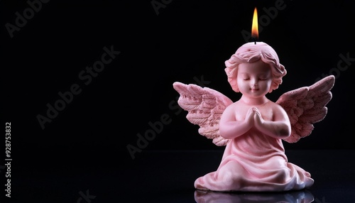 Cute angel shaped candle burning on a black background photo